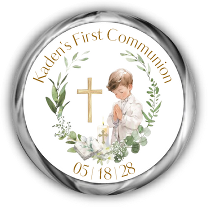 A personalized first communion sticker. The white center shows a watercolor illustration of a young boy in a white shirt praying, surrounded by green leaves, a gold cross, candles, and an open book.